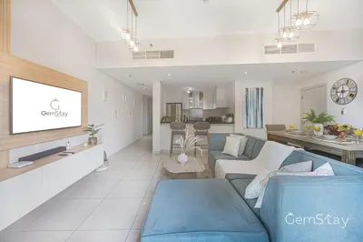 a living room with a blue couch and a kitchen at Beautiful Marina Skyline Serenity Spacious n Bright in Dubai