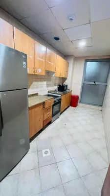 a kitchen with wooden cabinets and a stainless steel refrigerator at Mystic Nook Partition Room In Barsha Heights Tecom in Dubai