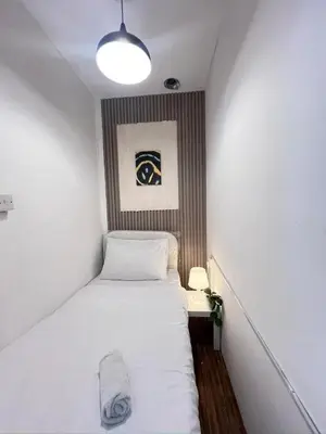 a small bedroom with a white bed and a lamp at Skyline Stay Partition Room In Barsha Heights Tecom in Dubai