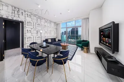 a dining room with a table and chairs and a tv at Apartments at Millennium Atria, Business Bay in Dubai