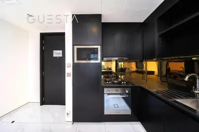 a kitchen with black cabinets and a stove top oven at Apartments at Millennium Atria, Business Bay in Dubai