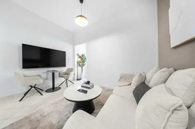 a white living room with a white couch and a table at StayShort - Chic studio in Production City that sleeps 4 in Dubai