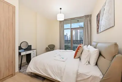 a bedroom with a bed with a chair and a window at Bloomfields Spacious 2BR at Canal Bay in Dubai