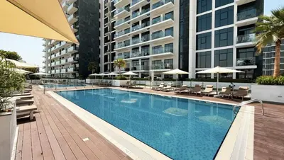 a swimming pool with chairs and umbrellas and a building at Luxury Studio with Burj Khalifa View in Dubai
