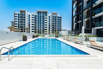 a swimming pool with chairs and buildings in the background at Luxury Studio With Burj Khalifa Views in Dubai