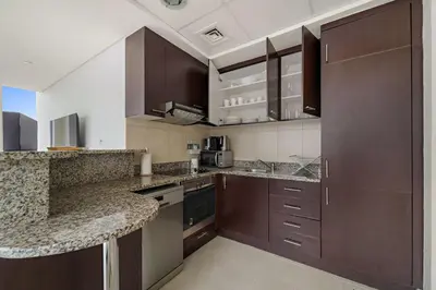 a kitchen with brown cabinets and a counter top at Silkhaus Expansive 2BDR in DIFC Sky Gardens in Dubai