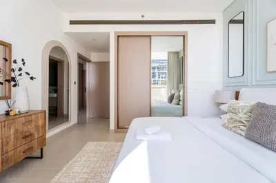 a white bedroom with a large bed and a mirror at GuestReady - Spacious 1 bedroom apartment in Dubai