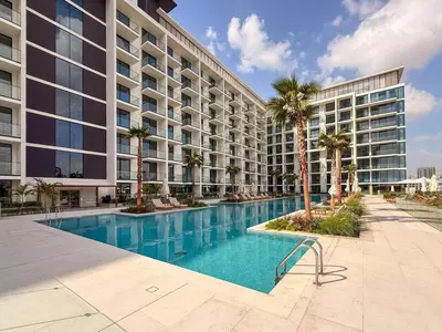 a large apartment building with a swimming pool and palm trees at GuestReady - Spacious 1 bedroom apartment in Dubai