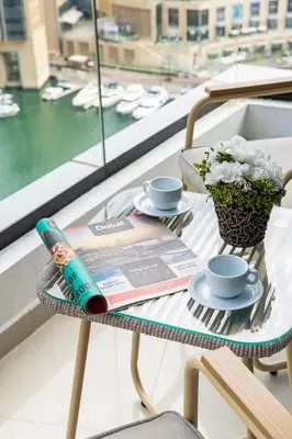 a table with a magazine and cups and a drink on it at Airstay - Full Marina Views - Coastal Studio - Monthly Offer Available! in Dubai