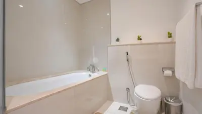 a white bathroom with a tub and a toilet at Deluxe Pool View apartment in BLVD Crescent Downtown Dubai by Norbu Holiday Homes in Dubai