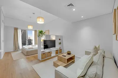 a white living room with a couch and a tv at Waves - Modern Lakeview Studio - Cozy & Bright in Dubai