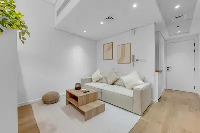 a white living room with a couch and a table at Waves - Modern Lakeview Studio - Cozy & Bright in Dubai