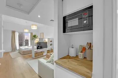 a white living room with a microwave and a living room at Waves - Modern Lakeview Studio - Cozy & Bright in Dubai