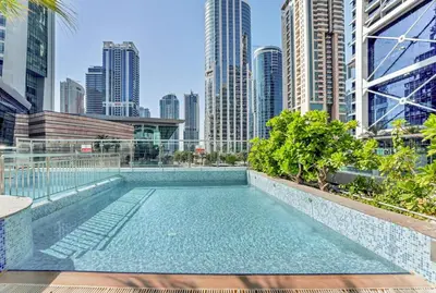 a swimming pool with a city skyline in the background at Waves - Modern Lakeview Studio - Cozy & Bright in Dubai