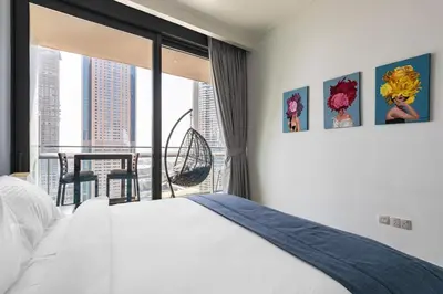 a bedroom with a bed and a balcony with a table at Burj Vista Modern Comfort - 1BR with Pool, Gym and Scenic views in Dubai