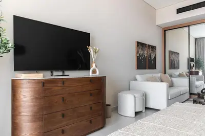 a living room with a flat screen tv on a wooden dresser at Trillionaire Bayhouse One- Private Jacuzzi, Sauna, pool and gym in Dubai