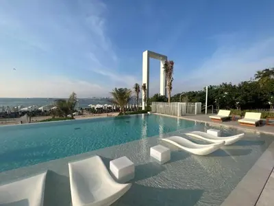 a swimming pool with white lounge chairs and the ocean at Vacationer l Chic 2 Bedroom l Sea Views l Private Beach Access in Dubai