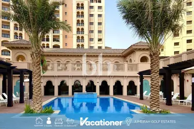 a swimming pool in front of a building with palm trees at Vacationer l Cozy 1 Bed l Jumeirah Golf Estate l Free Pool, Gym in Dubai