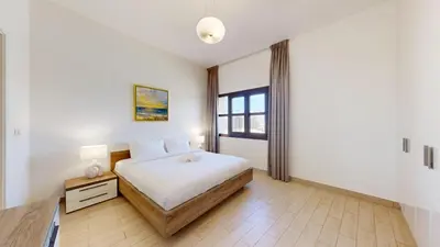 a white bedroom with a bed and a window at Vacationer l Cozy 1 Bed l Jumeirah Golf Estate l Free Pool, Gym in Dubai