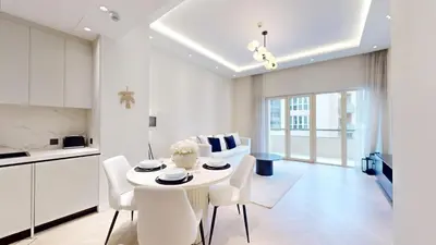 a white kitchen and dining room with a table and chairs at Vacationer l Modern Aesthetic 1 Bed l JVC l near Circle Mall in Dubai