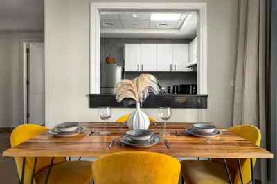 a dining room with a wooden table and yellow chairs at Modern 1BR Apartment - Burj Khalifa View - Pool & Terrace - Near Metro in Dubai