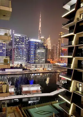 a city skyline at night with a river and buildings at Modern 1BR Apartment - Burj Khalifa View - Pool & Terrace - Near Metro in Dubai