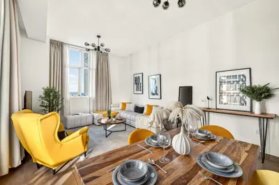 a living room with a table and yellow chairs at Modern 1BR Apartment - Burj Khalifa View - Pool & Terrace - Near Metro in Dubai
