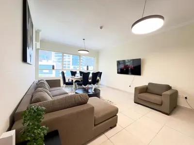 a living room with a couch and a table and chairs at Charming 2BR in Dubai Marina with Lake View in Dubai