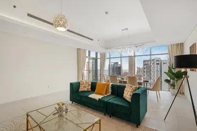 a living room with a green couch and a table at Luxury 2BR in Mada Residences - Walk to Dubai Mall in Dubai