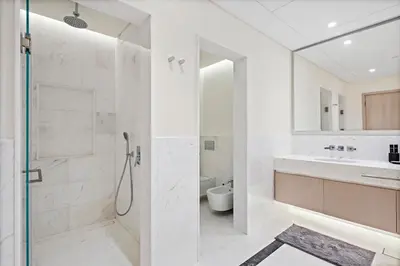 a white bathroom with a shower and a sink at Luxury 1BR in The Palm Tower Near Nakheel Mall in Dubai