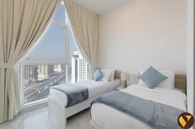 two beds in a room with a large window at Vogue Al Furjan Gemz by Danube near Ibn Battuta Mall, Three Bedroom plus Kids room Apartment with Balcony and Private Pool, Access to all amenities in Dubai