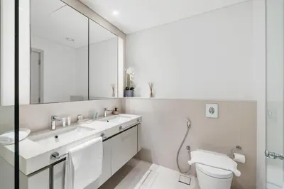 a bathroom with a sink and a toilet and a mirror at 2BR Beachfront Retreat with Palm and Dubai Eye Views in Dubai