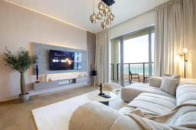 a living room with a white couch and a tv at Stylish Apartment in Le Pont Jumeirah Near Beach in Dubai