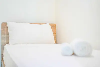 a bed with a white pillow and two clocks at TRPS - District One Residences, MBR - Brand New 3BR plus Maids, Lagoon View, Fully Furnished in Dubai