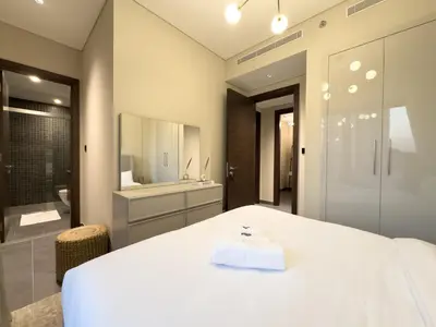 a bedroom with a large white bed and a bathroom at Werova-Cozy 2-Bedroom Apartment w Stunning Views in Dubai