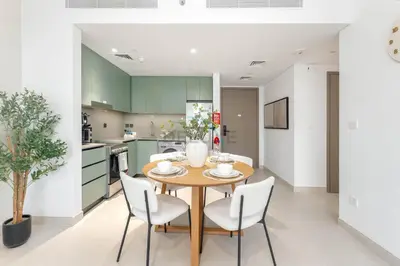 a kitchen and dining room with a wooden table and chairs at Steps from the Park, Mall and The Green Planet, Minutes to Metro with Easy Access to Downtown Attractions, Myrtle, Al Wasl by Deluxe Holiday Homes in Dubai