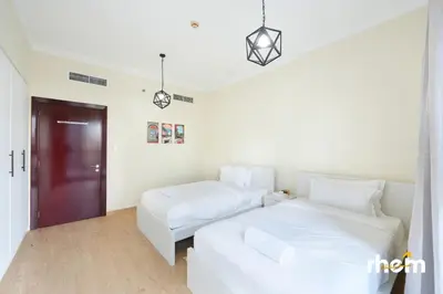 a white bedroom with two beds and a couch at Brand New 2-BR Panoramic View - Near Marina & JBR in Dubai