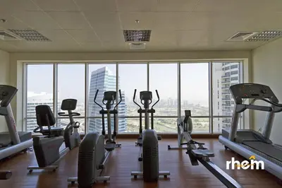 a gym with several tread machines and a large window at Brand New 2-BR Panoramic View - Near Marina & JBR in Dubai