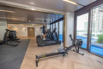 a man is on a treadmill in a gym at Bright Studio with Pool Access - Azizi Riviera in Dubai