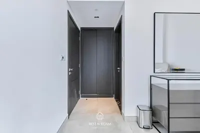a hallway with black cabinets in a white room at Brand New 1B with Burj Khalifa View in Business Bay in Dubai