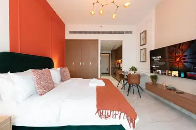 a bedroom with a large bed and a flat screen tv at Elegant Studio with Balcony & Pool in Dubai Studio City in Dubai