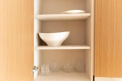 a cupboard with a bowl and glasses on it at Elegant Studio with Balcony & Pool in Dubai Studio City in Dubai