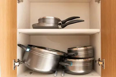 a pantry with pots and pans on a shelf at Elegant Studio with Balcony & Pool in Dubai Studio City in Dubai