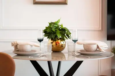 a table with plates and glasses and a plant on it at Elegant Studio with Balcony & Pool in Dubai Studio City in Dubai