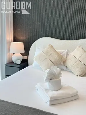a white bed with pillows and a towel on it at Great Cozy Studio on Palm Jumeirah in Dubai