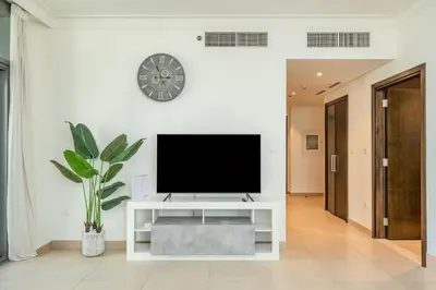 a living room with a tv on a white wall at PVH - Creek Residences South T3 - Harbourfront 2BR in Dubai