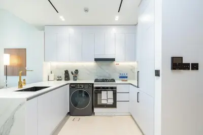 a kitchen with white cabinets and a dishwasher at PVH - Pristine 1BR Minutes to Circle Mall - Binghatti Amber in Dubai