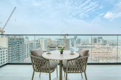a table and chairs on a balcony with a view of a city at PVH - Pristine 1BR Minutes to Circle Mall - Binghatti Amber in Dubai