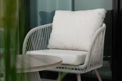 a wicker chair with a pillow on it next to a table at Modern 1BR Apartment with Private Pool in JVC in Dubai