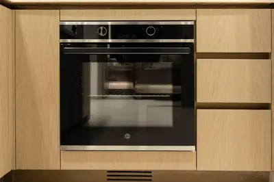 a black oven in a kitchen with a wooden cabinet at Elegant Apartment with Balcony Pool & Parking in Dubai